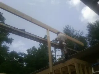 Carpenter setting a ridge beam over a new addition frame — Ice Dam Removal by Roofing Brothers in Batavia